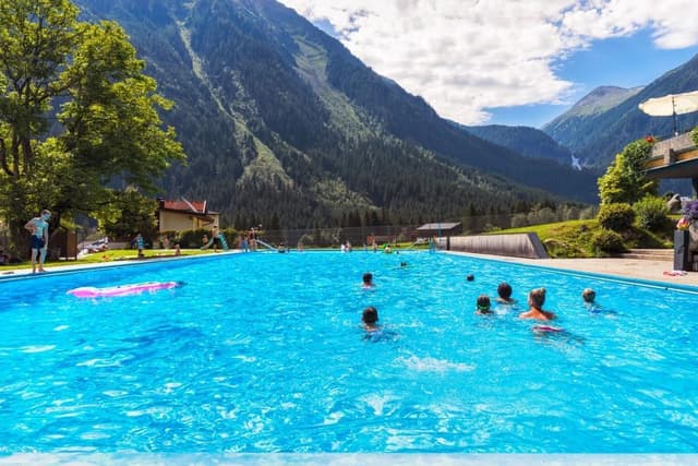 Een mooi zwembad midden tussen de bergen. Mensen zwemmen en ontspannen in het heldere blauwe water.