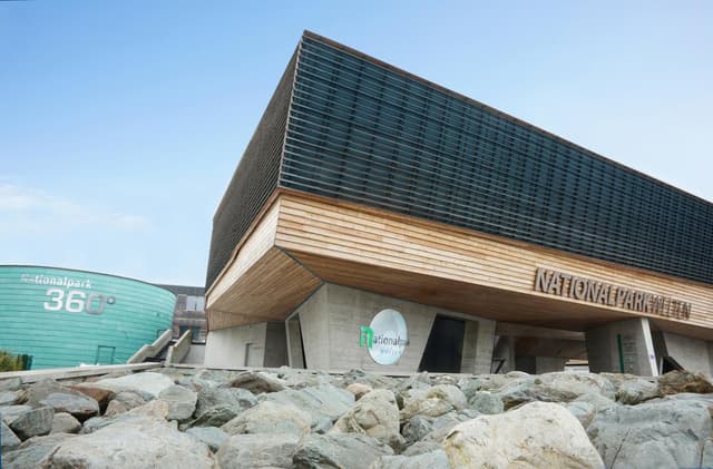 Centrum národního parku v Mittersillu s výraznou dřevěnou fasádou, budovou 360° kina a skalním prvkem v popředí